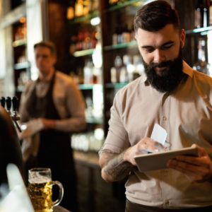 joven barista feliz trabajando bar navegando red panel tactil.jpg