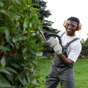 trabajador de jardin en uniforme corta arbustos hombre afroamericano con gafas y auriculares